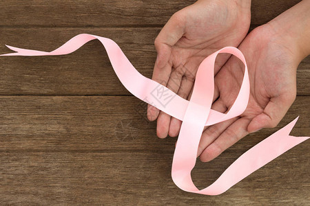 手中的粉红丝带符号放在木制背景上粉红丝带乳腺图片