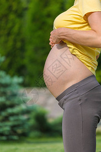 穿着黄色t恤的美丽孕妇在户外自然做产前瑜伽运动健身健图片