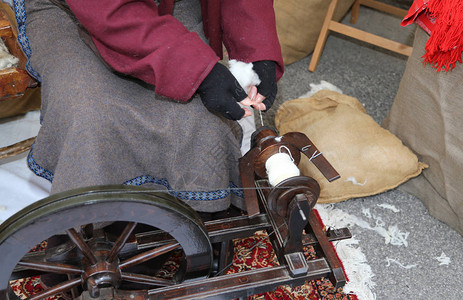 老年妇女用旧轮子缝羊毛衣图片