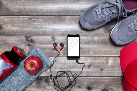红色苹果运动鞋耳机智能手机帽子毛巾和水瓶的顶端景象图片