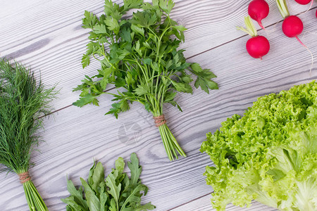 木桌上的混合蔬菜灰色纹理木材上的新鲜有机欧芹莳萝生菜芝麻菜和萝卜饮图片