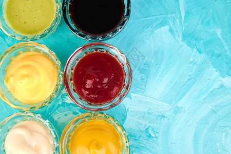一套不同的酱汁在蓝色背景的小碗里调味番茄酱芥末蛋黄酱图片