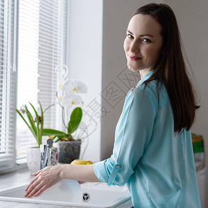 年轻快乐的女士在窗户前洗碗在水槽里图片