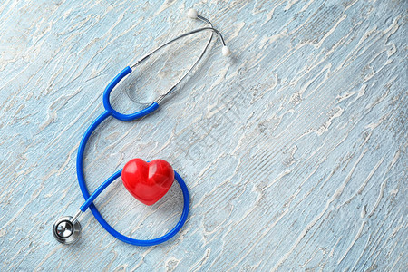 听诊器与木制背景上的红色心医疗保健概念图片