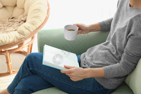 青年妇女在家里读书时喝图片