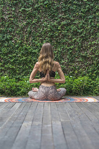 女人在莲花里练瑜伽的后方装扮成背着绿色叶子在墙前图片