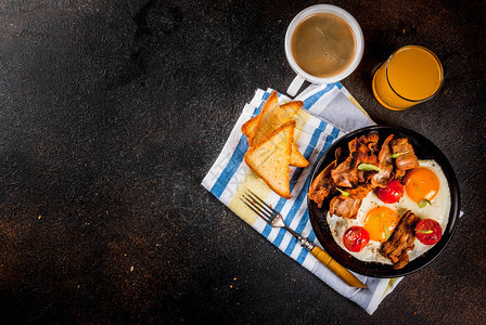 传统的自制美式英国早餐炸鸡蛋烤面包培根咖啡杯和橙汁暗底图片