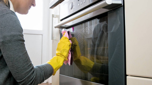 做饭后清洁脏烤炉的乳胶手套上年轻妇图片