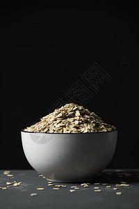 灰色桌子上装满燕麦片的白色陶瓷碗的特写图片