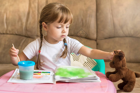 女孩在桌子边画着彩色画的小女孩儿图片