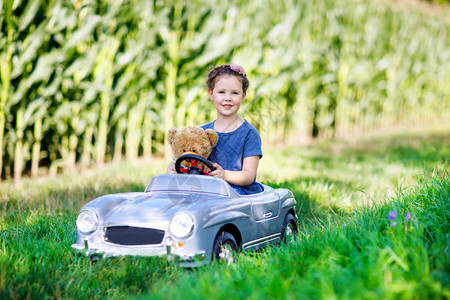学龄前小女孩开着老式旧玩具车图片
