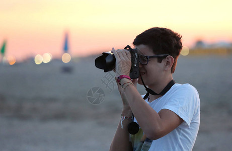 年轻男孩摄影师在沙滩上在夏图片