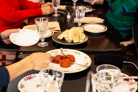 在家庭晚餐上手拿希腊酱和皮塔饼面包图片