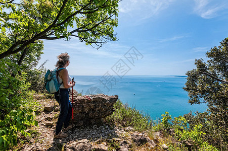 成熟的徒步旅行者女背着包在海上天空中展望旅行和积极的生活方式概念意大图片