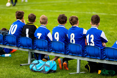 儿童足球队在板凳上儿童足球队员蓝色球衣的年轻男孩作为替补足球运动员足球俱乐部的青年足球运动图片