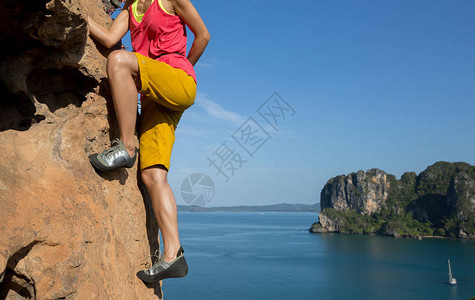 攀登在海边峭壁的女攀岩者图片
