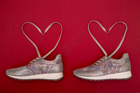 妇女运动鞋带条子以红背景的心形排列图片