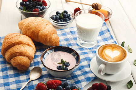 法式硬皮羊角面包麦片希腊酸奶一杯新鲜牛奶一杯热咖啡和大量甜浆果图片