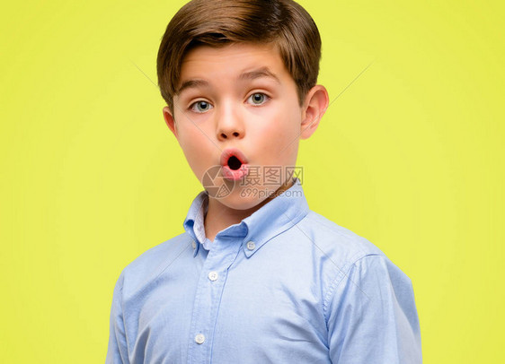 青绿眼睛的长胖小孩快乐和惊异的欢呼声在黄色背景图片