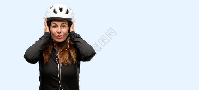 中年骑自行车的妇女使用耳机遮住耳朵图片