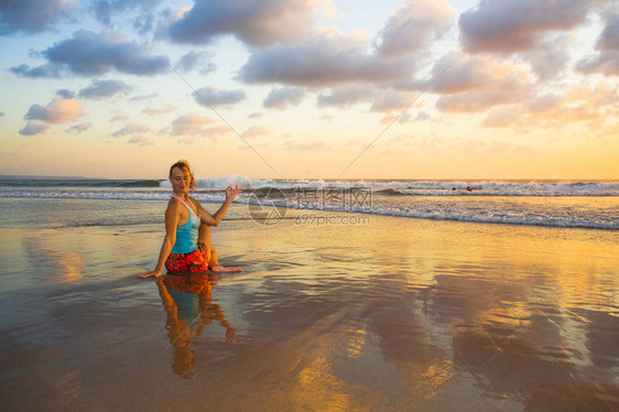 年轻健康和有吸引力的运动女在海滩日落瑜伽练习锻炼坐在潮湿的阳光下在海前冥想和放松锻炼身心护理和图片