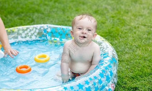 在后院的充气游泳池里游泳时微笑着的男图片