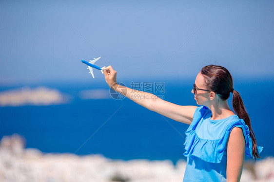 拥有玩具飞机的旅游美女手握着古希腊村背景图片