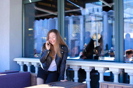 女青年在咖啡馆与智能手机上的朋友交谈图片