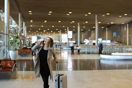 年轻女子带着手提箱走进机场候机室图片