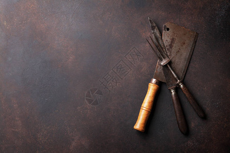 屠宰机和厨房用具旧的肉刀和叉子放在石板上您的文字最宽视图图片