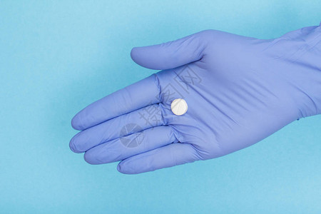 穿着蓝色乳胶手套手掌上戴白药片的女医生紧握手图片