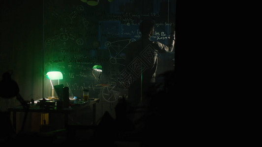 一个男人晚上在玻璃板上写字库存一个不知名的天才独自在黑图片