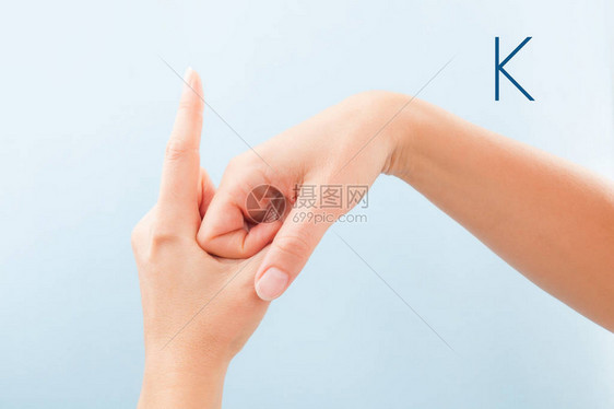 女用蓝色背景孤立的手显示聋哑人BSL字母K图片
