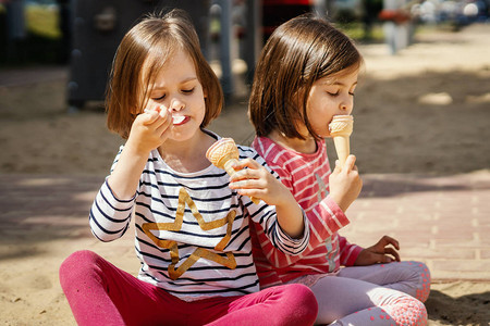 两个小女孩夏天坐在操场上吃冰淇淋图片