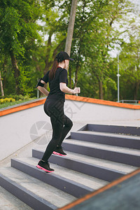 身穿黑色制服戴着耳机的年轻运动美女黑发女孩做运动锻炼训练和跑步图片