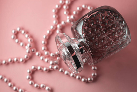 粉红色背景中带有珍珠装饰的女香水瓶图片