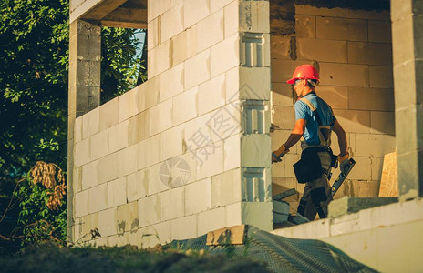 白种人的房子建筑工人在硬帽与精神水平以检查必要的住房级别图片