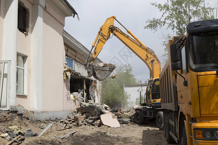 车轮上的挖掘机在自卸卡车的身中装载建筑垃圾和旧建图片