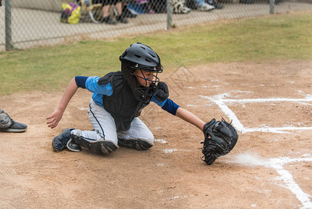 高手小联盟棒球猎手从泥土中挖出一个低点球当它把粉笔尘图片
