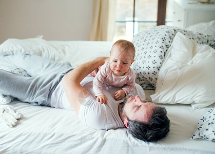 父亲和一个不开心的小孩女在床上睡觉时在家图片