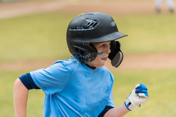 近距离接近小联盟棒球运动员的脸显示眼睛黑和集中向第一垒图片