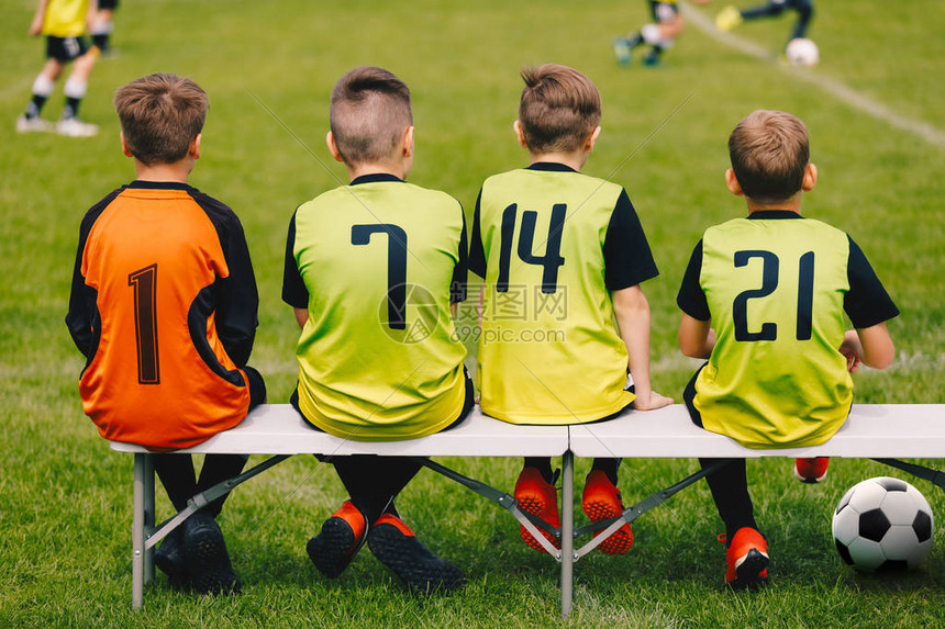 坐在长凳上的儿童足球队儿童足球队员穿着球衣作为替补足球员的年轻男孩足球俱乐部的青年足球图片