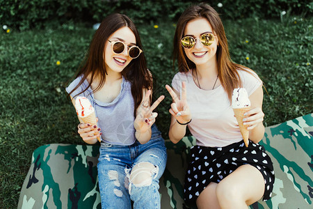 坐在街上草地上吃冰淇淋的两名年轻女子的肖像图片