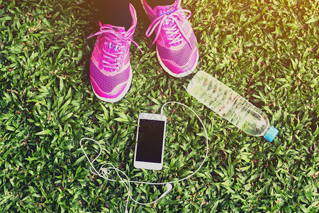 携带智能手机和水瓶撒在草背景图片