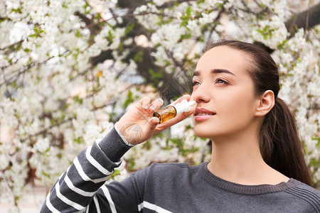 青春女子在开花树附近使用鼻涕图片
