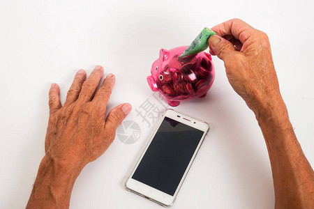 亚洲高级将笔记插入红色存钱罐储蓄退休计划退休人员图片