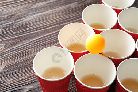 木桌上啤酒乒乓球的杯子和球图片