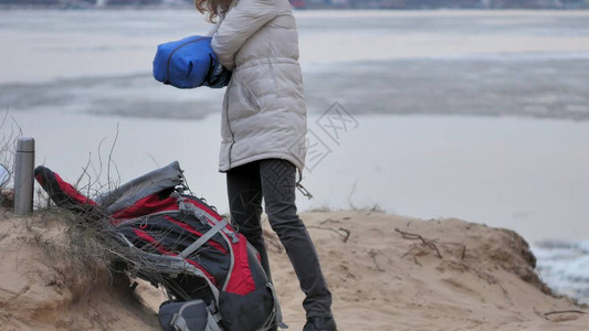 身戴红色帽子的迷人年轻旅游女客在沿海森林附近收集一个图片