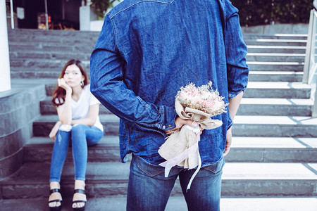英俊的男朋友在他背后藏着一束花有魅力的帅哥今天见到她是为了弥补他美丽的女朋友他的女朋友生闷气图片