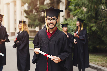 年轻的微笑男子在大学毕业那天与多民族学生站在一起教育资图片